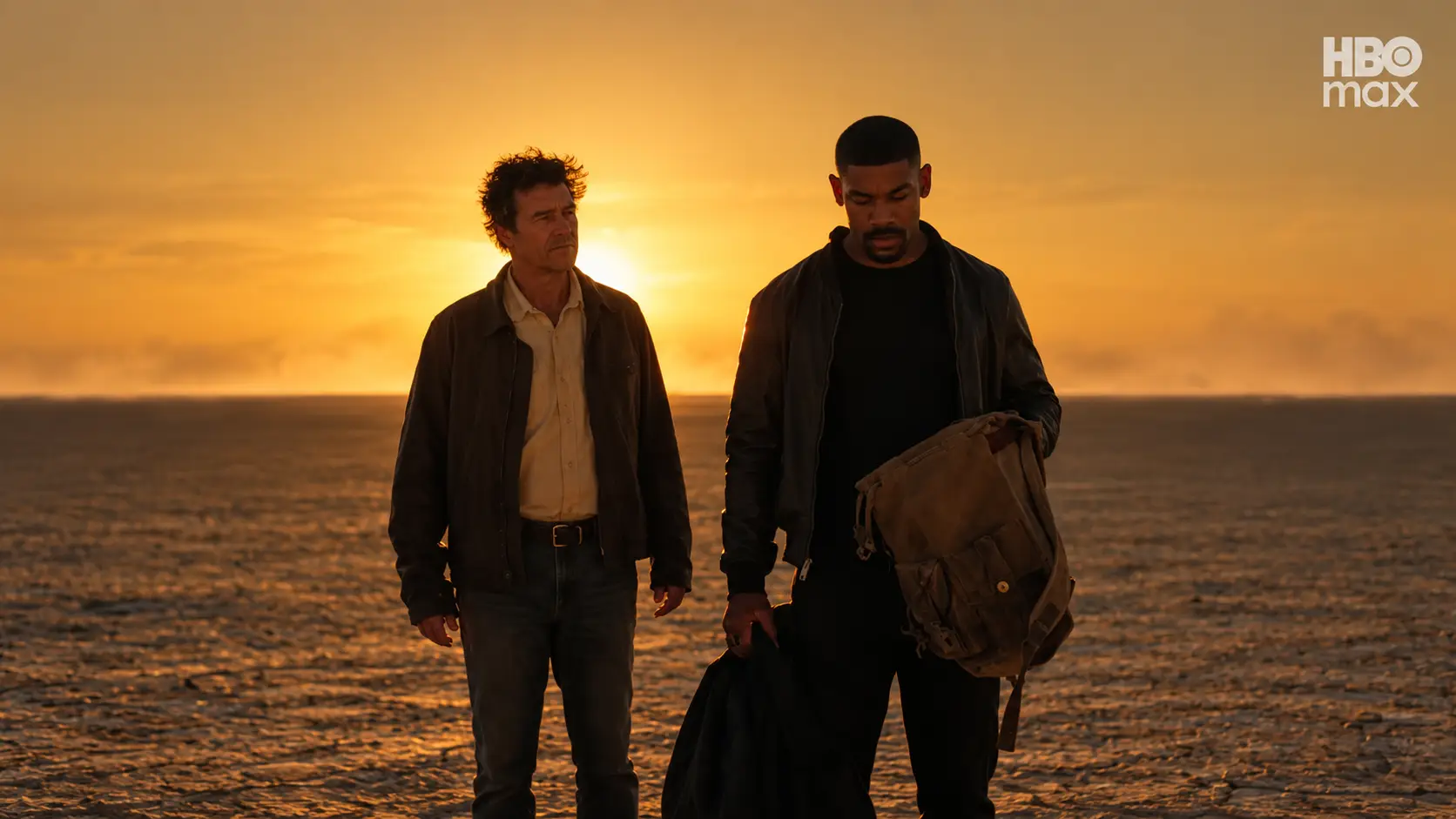 Hal Jordan e John Stewart caminham por uma paisagem árida ao pôr do sol, carregando bolsas.
